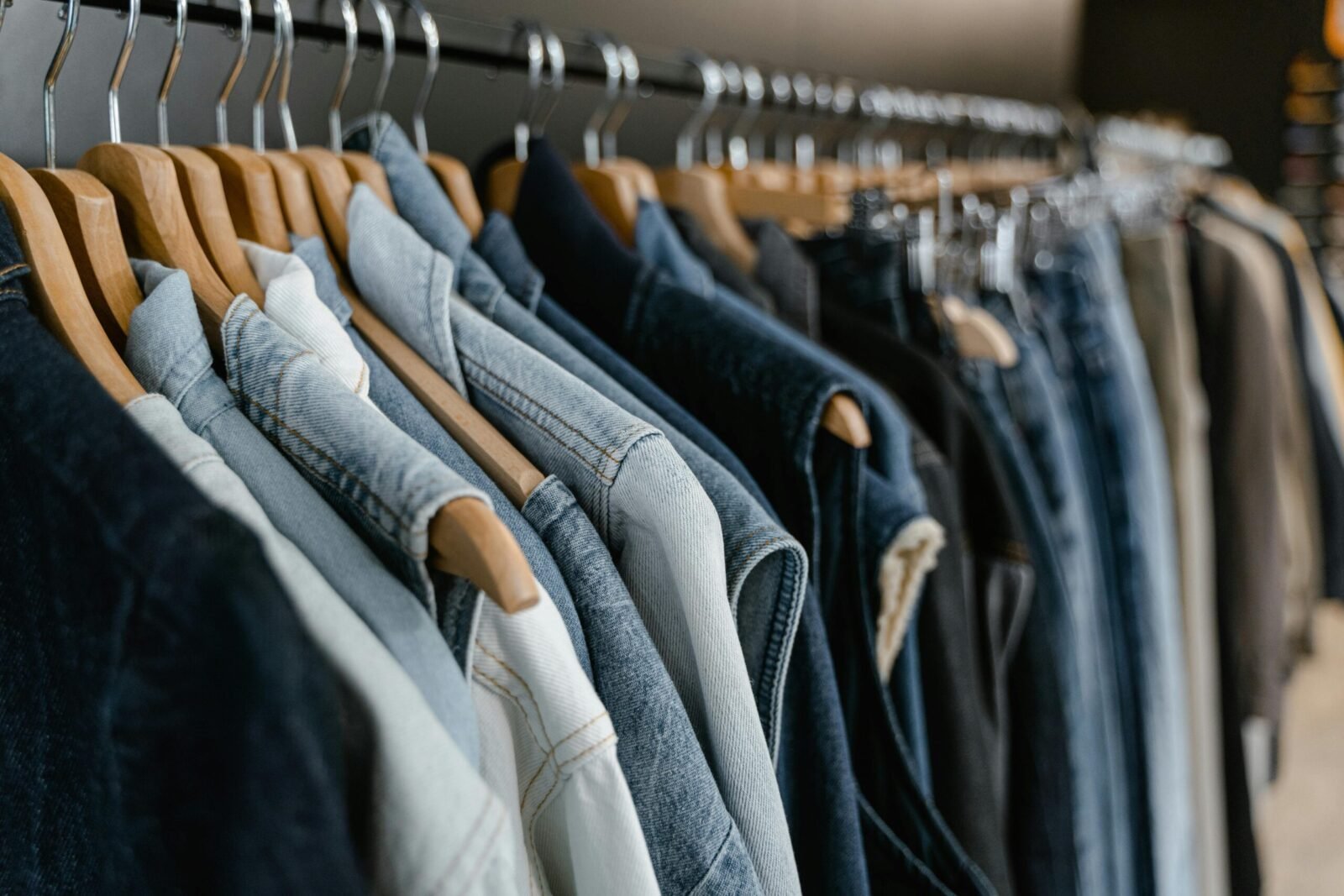 A close-up view of various denim jackets hanging on a clothes rack indoors.